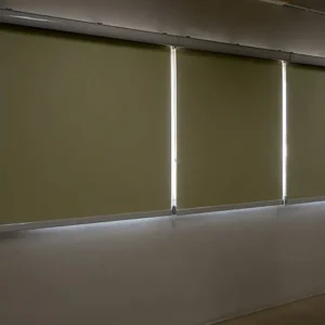 Beige blackout roller blinds installed on multiple windows in a modern interior.