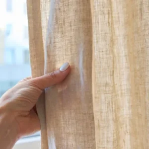 beige fabric curtain allowing soft natural light into room near window
