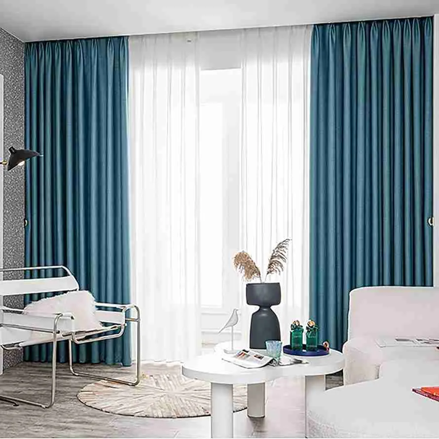 Teal blue curtains with white sheer panels in a modern Dubai living room beside a large window.
