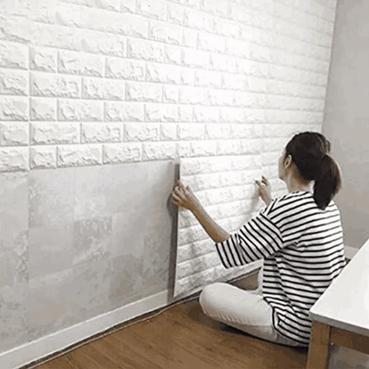 Woman applying white brick-style wallpaper panels on a wall in a Dubai home interior