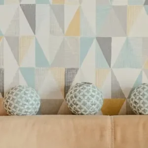 geometric patterned wallpaper behind sofa with decorative cushions.