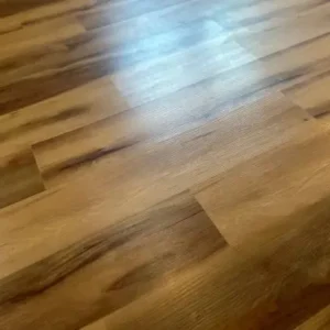close up of glossy brown vinyl plank flooring with wood texture finish.