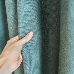 hand touching thick green fabric curtain showing texture and quality