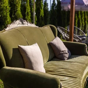 green vintage upholstered couch in an outdoor garden seating area.