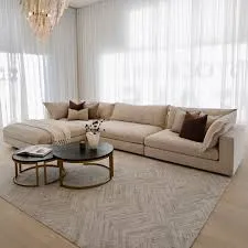 Beige sectional upholstered sofa in a luxury Dubai interior with white curtains and round nesting tables.