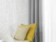 Grey and white curtains in a minimalist Dubai room with accent chair and brick wall.