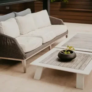 rattan outdoor sofa with beige cushions in garden seating area.