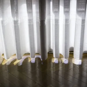 sheer curtains casting soft light patterns on wooden floor