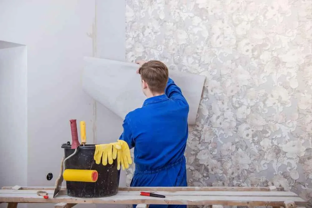 Worker installing floral wallpaper on a wall using tools during a home renovation project in Dubai
