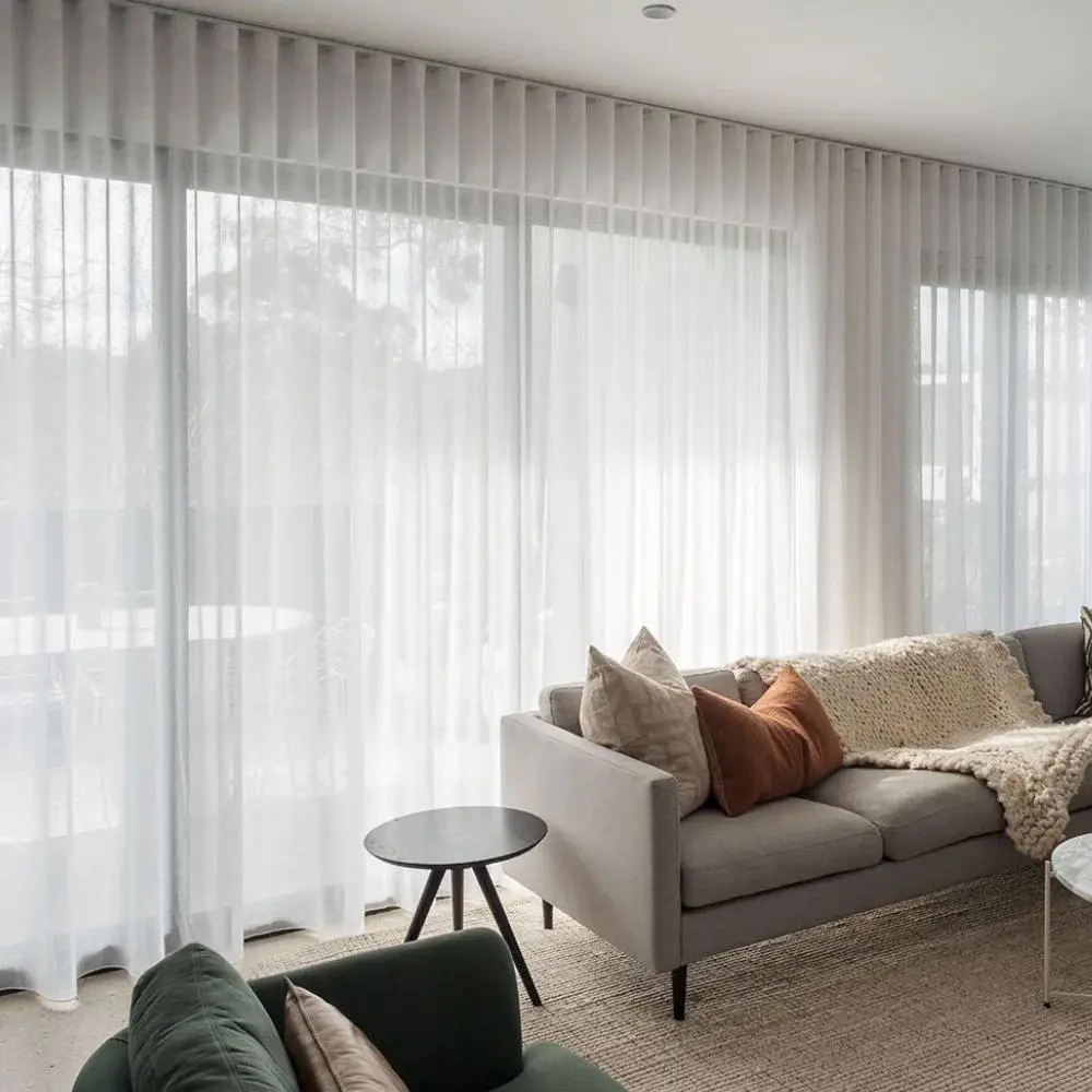 White blackout curtains layered across wide bedroom windows in a modern Abu Dhabi home.
